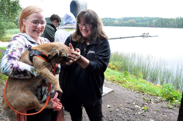 Rommi-koira pääsi starttipajalaisten mukaan Oinasjärven kalastusretkelle. Rommi on Martta Mäkisen sylissä ja vieressä koiraa paijaa starttipajan valmentaja Mari Vasama