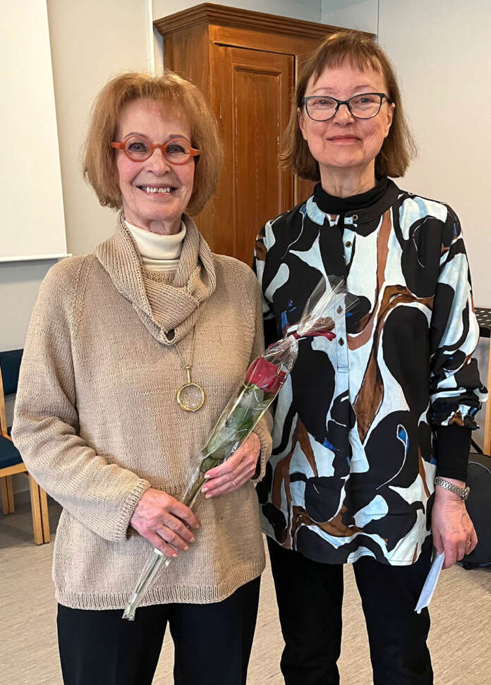 Kaari Utriolle ruusun antoi vapaaehtoisena tilaisuudessa toiminut Hanna-Liisa Kärki (oik.). Utrio kertoi tätä nykyä nauttivansa loppuelämän lomasta, jossa ei tarvitse suorittaa mitään, vaan saa itse valita, mitä haluaa tehdä. Ämyrin maastot ja luonto tuovat hänelle iloa.